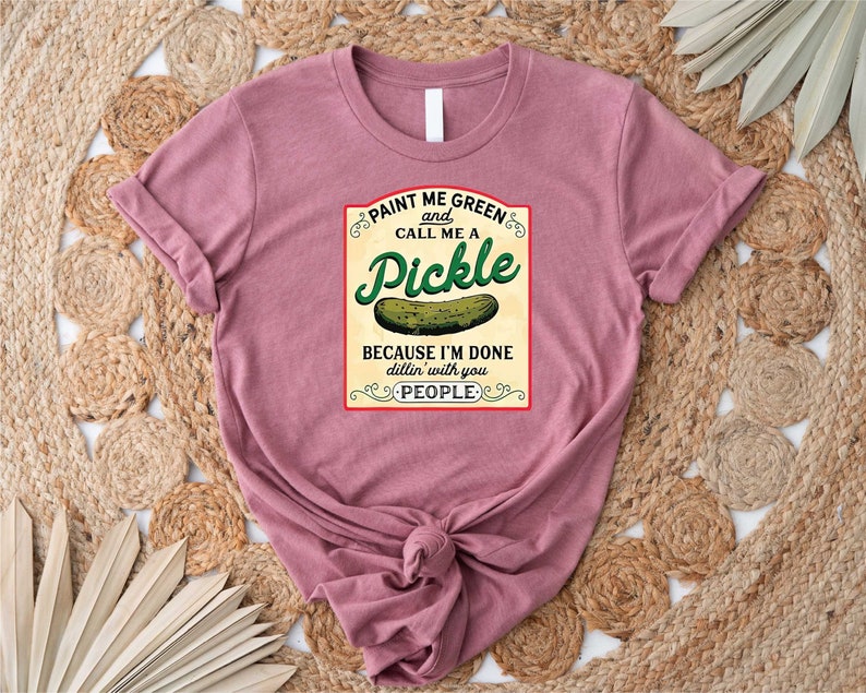 K&ouml;nnte beinhalten: Ein pinkfarbenes T-Shirt mit einer Grafik im Vintage-Stil, auf dem steht: "Malt mich gr&uuml;n und nennt mich eine Gurke, weil ich es satt habe, mit euch Leuten zu dilln".