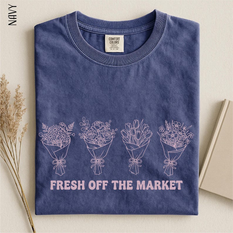 A navy blue t-shirt with a graphic design of four bouquets of flowers and the text "FRESH OFF THE MARKET" printed on it.