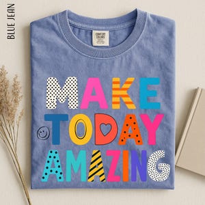 A blue t-shirt with the text "MAKE TODAY AMAZING" printed on it, along with various colorful and playful lettering designs.