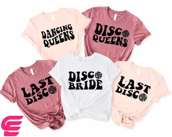 May include: Four t-shirts with a disco theme. The shirts are pink, white, and a darker pink. The shirts have the text "Last Disco", "Disco Bride", "Disco Queens", and "Dancing Queens" with a disco ball graphic.