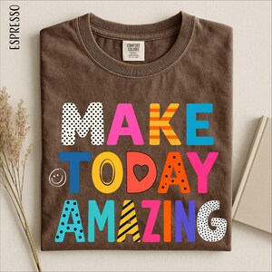 a brown t-shirt with a colorful and playful design that says "MAKE TODAY AMAZING" in a vibrant and creative font.