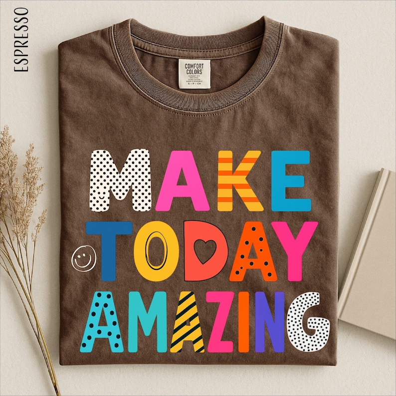 a brown t-shirt with a colorful and playful design that says "MAKE TODAY AMAZING" in a vibrant and creative font.