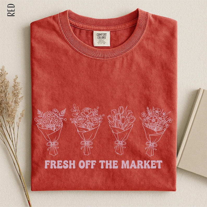 a red t-shirt with a graphic design of four bouquets of flowers, accompanied by the text "FRESH OFF THE MARKET" printed on it.