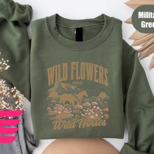a green sweatshirt with wild flowers and wild horses on it