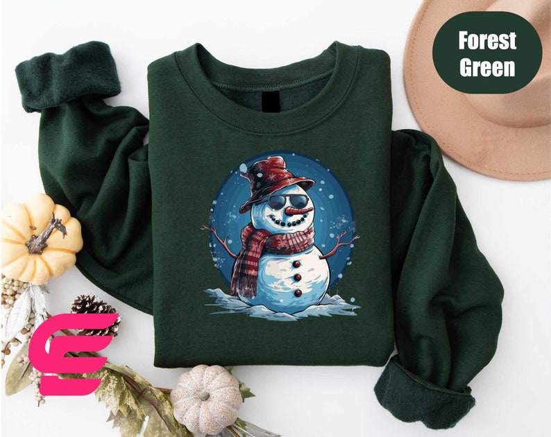 a green shirt with a snowman wearing a hat and scarf