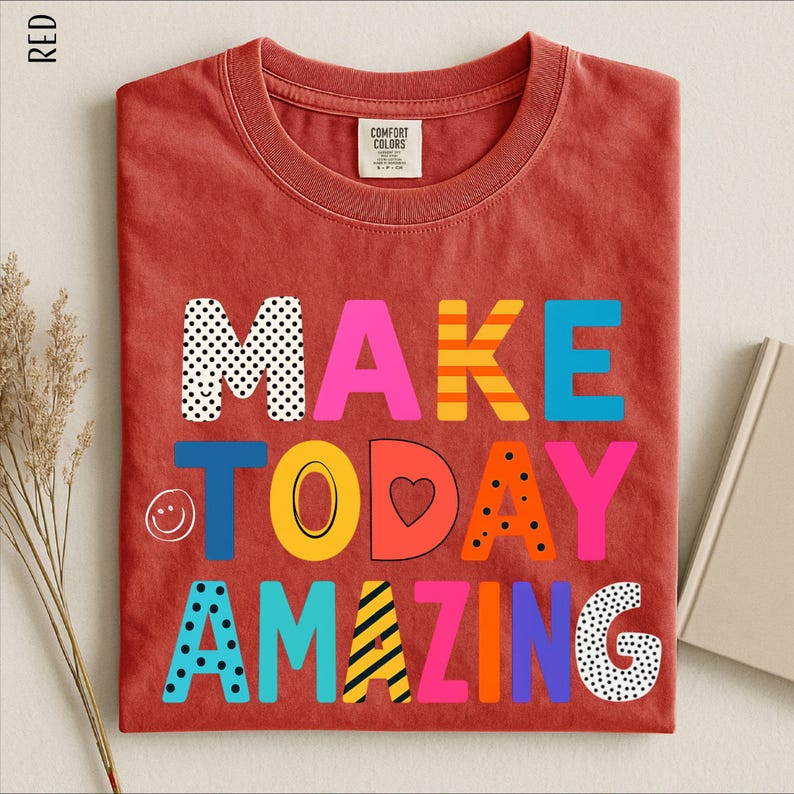 A red t-shirt with the text "MAKE TODAY AMAZING" printed on it, along with various colorful and playful lettering designs.