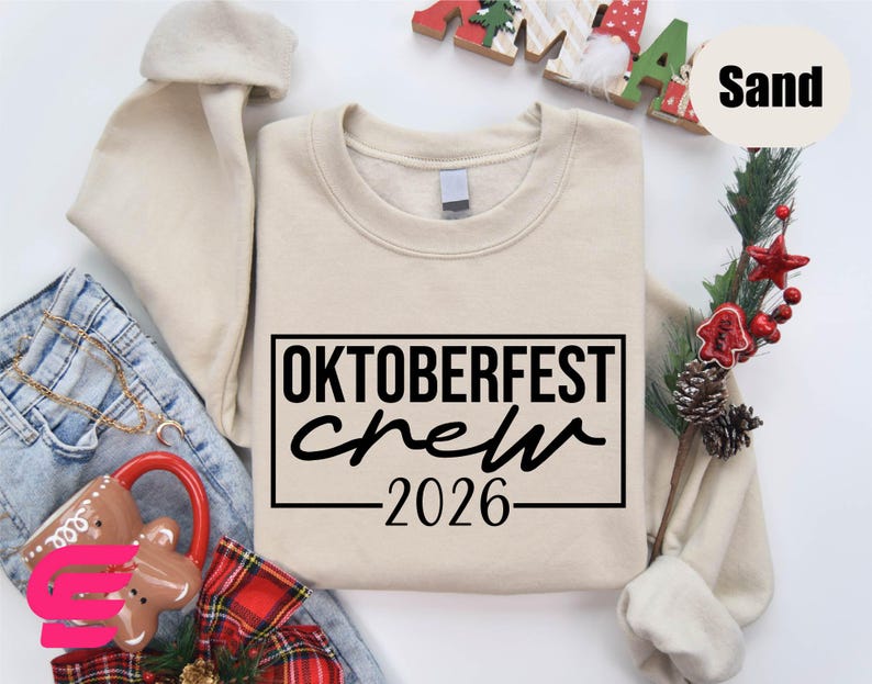 a beige sweatshirt with the text "OKTOBERFEST CREW 2026" printed on it, along with some other clothing items and holiday decorations.