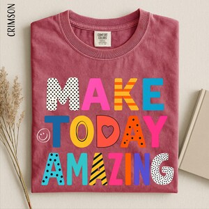 A red t-shirt with the text "MAKE TODAY AMAZING" printed on it, along with various colorful and playful lettering.
