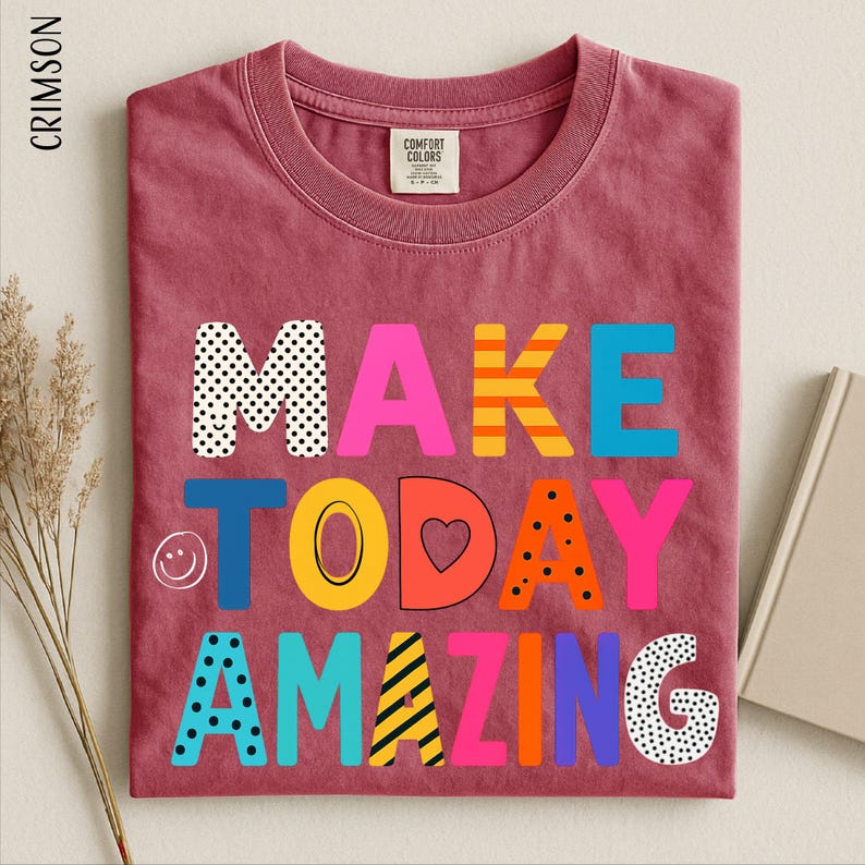 A red t-shirt with the text "MAKE TODAY AMAZING" printed on it, along with various colorful and playful lettering.