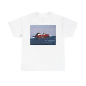 Puede incluir: Una camiseta blanca con un barco rojo y blanco sobre un fondo azul y blanco. El texto en la camiseta dice "R.R.S. Ernest Shackleton (Re-commissioned) British Antarctic Survey 1994-2023".