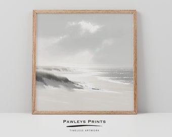 May include: A black and white photograph of a beach scene with sand dunes and the ocean in the distance. The photo is framed in a light wood frame.