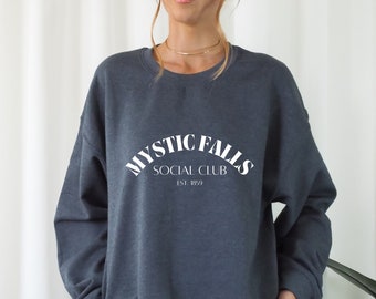 May include: A dark gray sweatshirt with a white graphic print that reads "Mystic Falls Social Club Est. 1859".