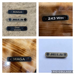 May include: A collage of black and tan rectangular tags with text. The tags read "MAGA", ".223/5.56", "DOG DOWN", and "243 WIN". Each tag has two screw holes on either end.