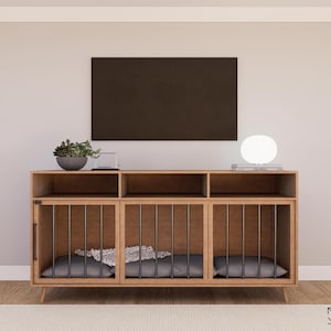May include: A wooden dog crate with three compartments, each with a black metal gate. The crate is sitting on a wooden stand with a shelf above. There is a plant, a lamp, and a framed picture on the shelf.