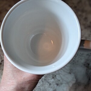 May include: A white ceramic mug with a smooth, glossy finish. The mug is empty and appears to be new.