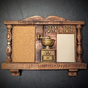 May include: A brown wooden wall organizer featuring a cork board on the left, a white memo board on the right, and a central coffee grinder relief. The text START TODAY WITH A SMILE is embossed above the grinder. The frame has decorative pillars.