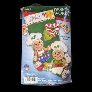 Peut inclure: Un kit de bas de Noël en feutre Design Works avec un fond vert. Le kit présente des motifs de boulangers en pain d'épices, des cannes en bonbon et une étoile. Le texte "Leah" est sur le bas. Le kit mesure 45.7 cm.