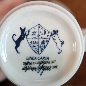 May include: White ceramic mug base with a navy blue illustration. A shield design is flanked by a black dog and a pug. The text "LINEA CARTA" and "DISHWASHER & MICROWAVE SAFE" are printed below the illustration.