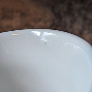 May include: A white ceramic mug with a small chip on the inside rim.