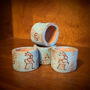 May include: Four teal blue ceramic planters with a copper glaze and a stylized bird design. The planters are stacked on top of each other.