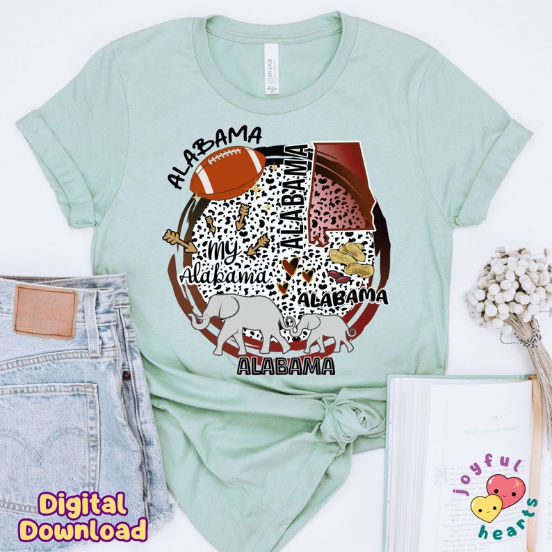 K&ouml;nnte beinhalten: Ein hellgr&uuml;nes T-Shirt mit einem Grafikdesign, das einen Fu&szlig;ball, Erdn&uuml;sse, Elefanten und das Wort "Alabama" mehrmals wiederholt zeigt. Das Design ist in einem Kreis mit einem braunen und roten Rand.