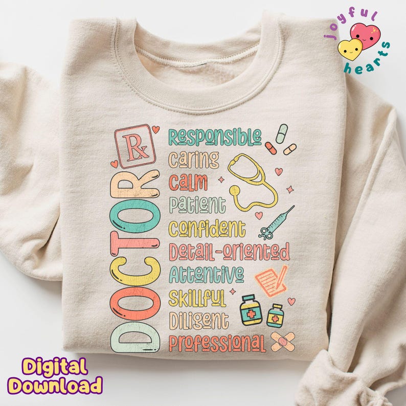 May include: A beige sweatshirt featuring a graphic design that reads "DOCTOR" in colourful letters. The graphic also includes a stethoscope, a pill bottle, a bandage, and other medical symbols. The words "Responsible, Caring, Calm, Patient, Confident, Detail-oriented, Attentive, Skillful, Diligent, Professional" are also included in the graphic.