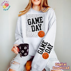 May include: A gray sweatshirt with the text "GAME DAY" in black and a basketball graphic. The text "Go, team, go! We're ready to win this show! Fight, team, fight! Let's take this game tonight! Shoot the ball, make that play today! Let's get loud. We're the best! Let's go!" is printed on the sweatshirt.