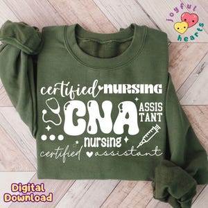 May include: Green sweatshirt with white text that reads "certified nursing CNA nursing certified assistant" with a stethoscope, heart, stars, and a syringe graphic.