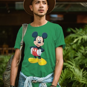 May include: A green t-shirt featuring a cartoon image of Mickey Mouse. Mickey Mouse is wearing red shorts and yellow shoes.