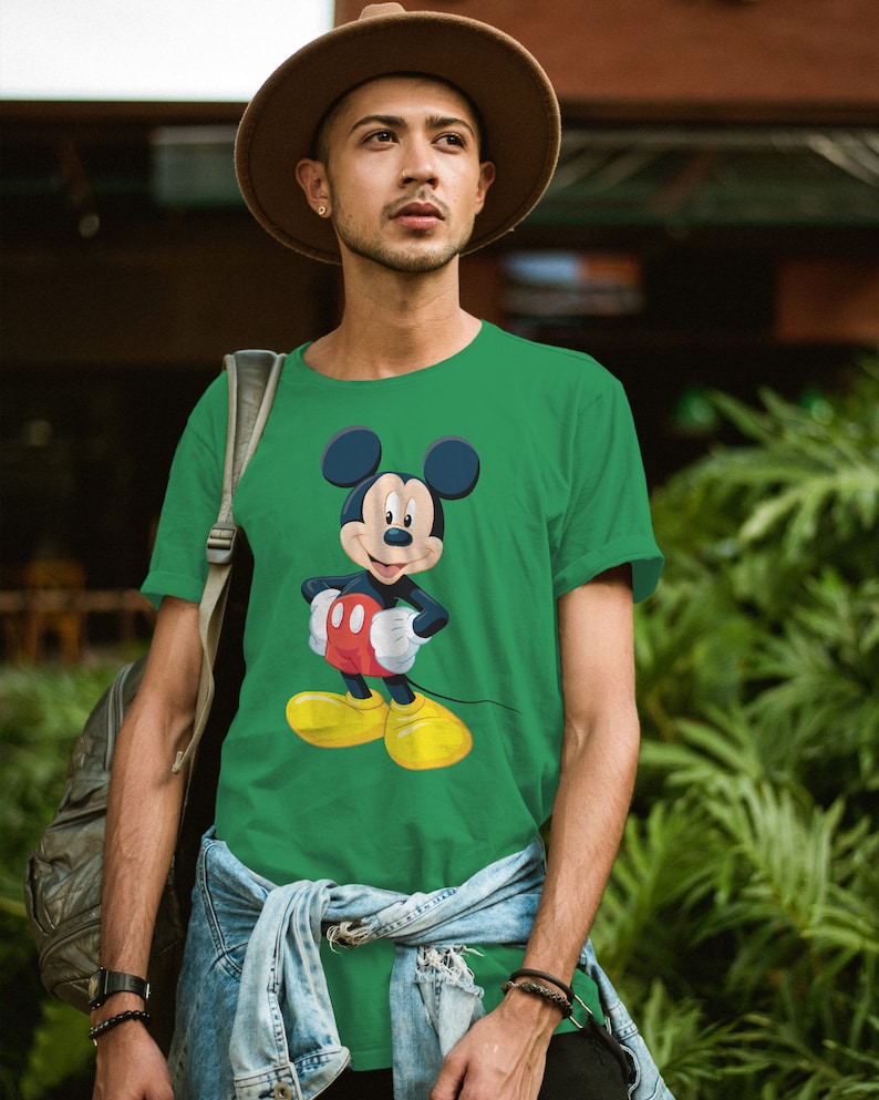 May include: A green t-shirt featuring a cartoon image of Mickey Mouse. Mickey Mouse is wearing red shorts and yellow shoes.
