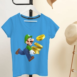 May include: A light blue t-shirt with a green and white cartoon character running and holding a stack of gold coins. The character is wearing a green hat and a green jumpsuit.