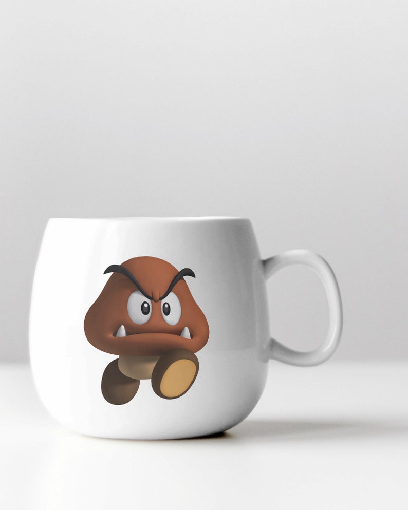 May include: White ceramic mug with a brown cartoon mushroom character with a frowning face and sharp teeth. The character is wearing a black hat.