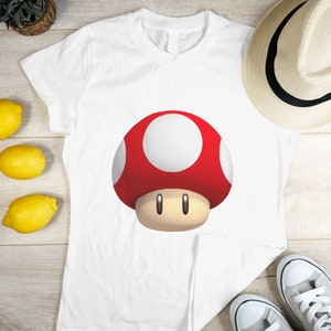 Peut inclure: T-shirt blanc avec un motif de champignon rouge et blanc.