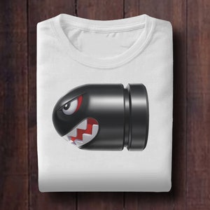May include: White t-shirt with a black and red cartoon bullet bill character from the Super Mario video game series.