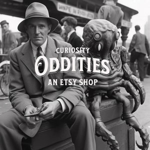 May include: A black and white photo of a man in a suit sitting next to a large, gray, alien-like creature. The man is holding a small object in his hand. The creature has large, round eyes and a long, thin snout. The text "Curiosity Oddities An Etsy Shop" is printed on the image.