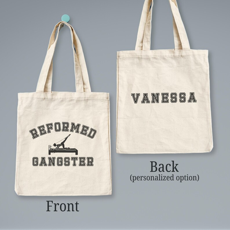 Pu&ograve; includere: Una borsa tote in tela bianca con testo nero. La parte anteriore della borsa dice "Reformed Gangster" con una silhouette di una persona che fa un esercizio di pilates. La parte posteriore della borsa ha il nome "Vanessa" in testo nero.