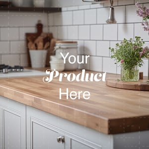 Puede incluir: Primer plano de una encimera de madera clara en una cocina con armarios blancos. La encimera está vacía, con el texto "Your Product Here" escrito en ella. Hay flores en un jarrón de vidrio y una tabla de cortar de madera en la encimera.