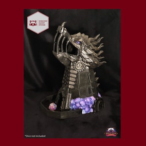 May include: A black metal dragon head dice tower with purple and gray accents. The tower is designed to hold dice and has a base for rolling. *Dice not included*