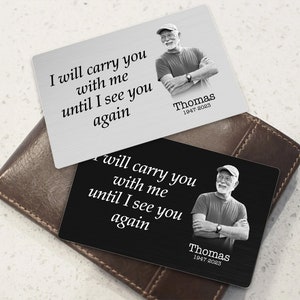 May include: Two wallet-sized memorial cards with a photo of a man and the text "I will carry you with me until I see you again." The cards are in black and silver with the name "Thomas" and the dates "1947-2023" printed on them.