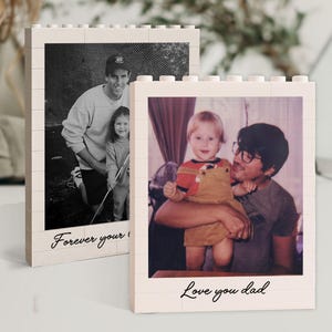 May include: Two cream-colored block-style photo frames. One frame displays a black and white photo of a man and child with the text "Forever your". The other frame shows a color photo of a man and child with the text "Love you dad".