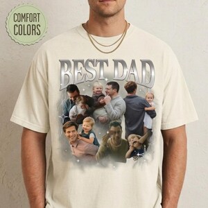 May include: Cream-colored t-shirt with the text "BEST DAD" in a silver, metallic font. The shirt features a collage of photos of a man with children. The words "COMFORT COLORS" are in a green circle.