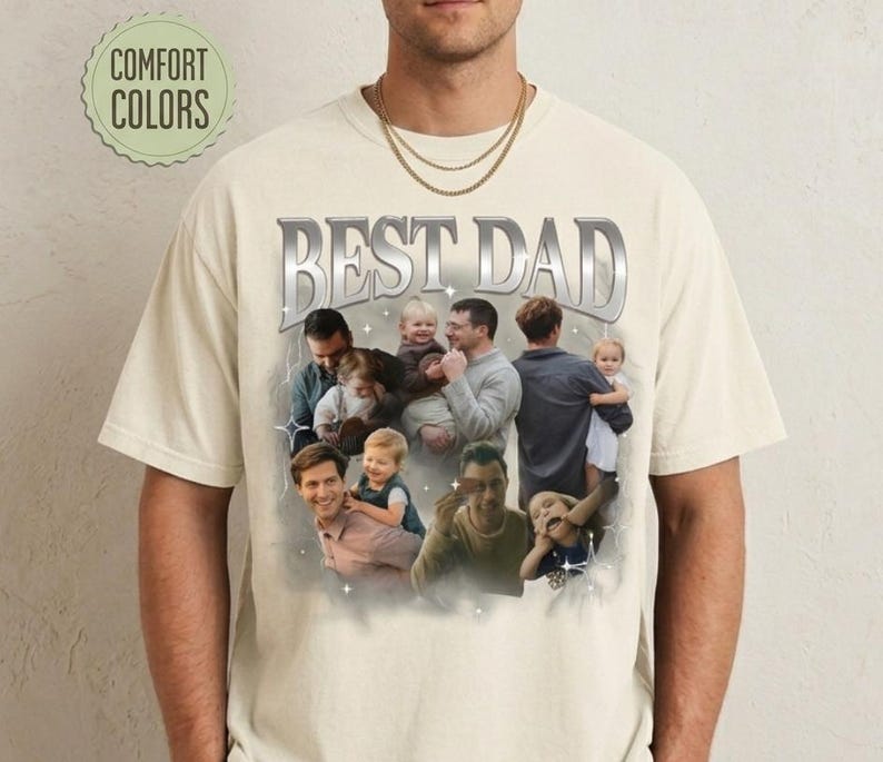 May include: Cream-colored t-shirt with the text "BEST DAD" in a silver, metallic font. The shirt features a collage of photos of a man with children. The words "COMFORT COLORS" are in a green circle.