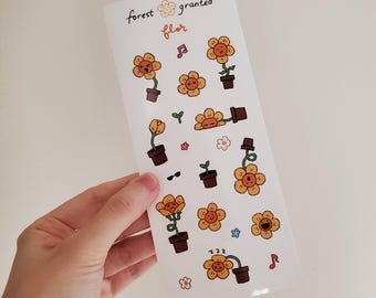 May include: A sticker sheet featuring various cartoon sunflowers in brown pots, with musical notes, sunglasses, and the text "forest granted flor". The sunflowers have smiling faces and are in different poses. The background is white.