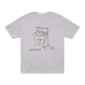 Puede incluir: Una camiseta gris con una ilustración en blanco y negro de un contenedor de hilo dental. El contenedor tiene la palabra "Floss" escrita en él con una flor amarilla. El texto "MONTANA" está escrito debajo del contenedor.