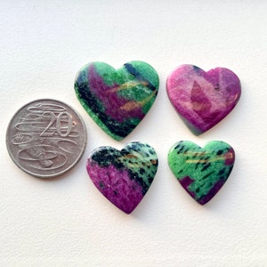 Peut inclure: Quatre pierres précieuses en forme de cœur de couleur verte et rose avec des inclusions noires et dorées. Les pierres précieuses sont approximativement de la taille d'une pièce de 20 centimes.