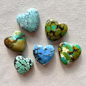 May include: Six heart-shaped stones in shades of blue, green, and brown. The stones have a textured appearance with unique patterns and veining. The arrangement showcases the variety of colors and designs in the collection.