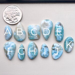 May include: Ten cabochon gemstones, labelled A through K, in various shapes and sizes. The stones are a light blue colour with white and brown markings. The stones are arranged in two rows.