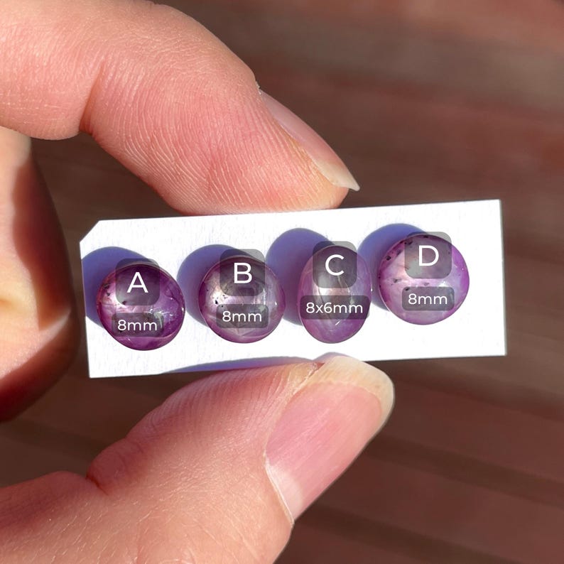 May include: Four oval-shaped, purple gemstones labeled A, B, C, and D, each with size details. Gem A, B, and D are 8mm. Gem C is 8x6mm. The gemstones are displayed on a white card.