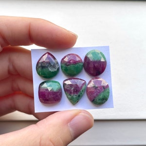 May include: Six faceted gemstones with a mix of red and green colors. The gemstones are in various shapes, including teardrop, round, and square. The gems are displayed on a white card.