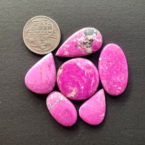 May include: Six pink and white cabochon stones with a mottled pattern. The stones are various shapes, including teardrop, oval, and round. The stones are approximately the size of a 20 pence coin.